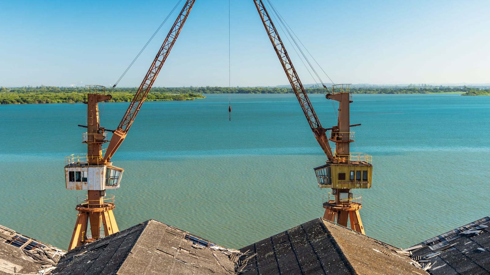 Twin cranes positioned over a tranquil river setting in Rio Grande do Sul, Brazil.