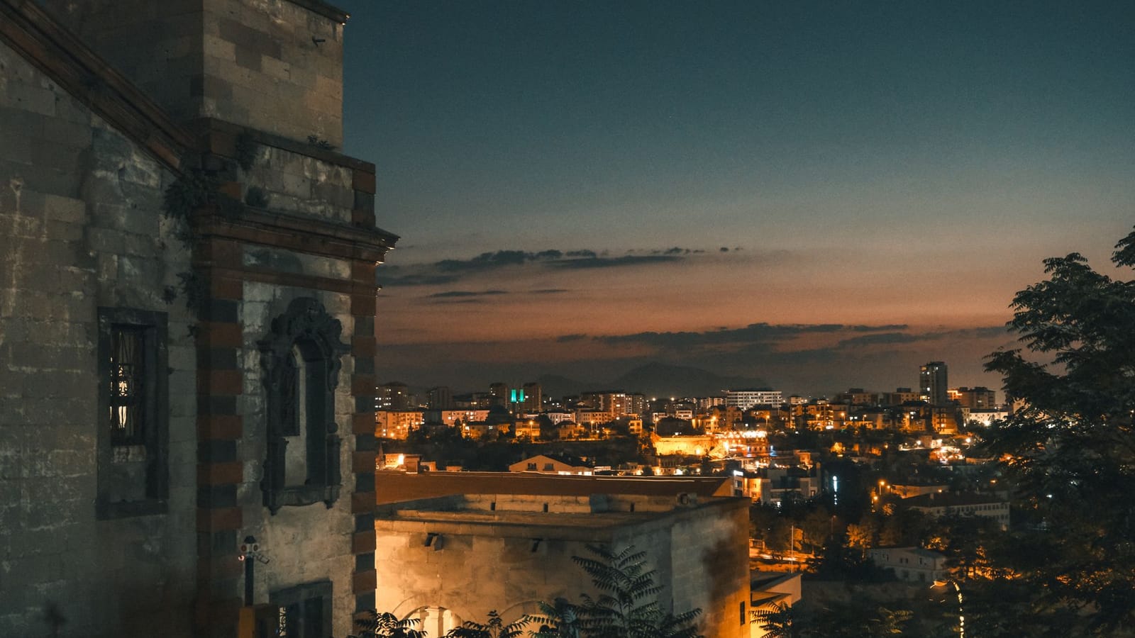 Scenic nighttime cityscape from a historic building with lights aglow.