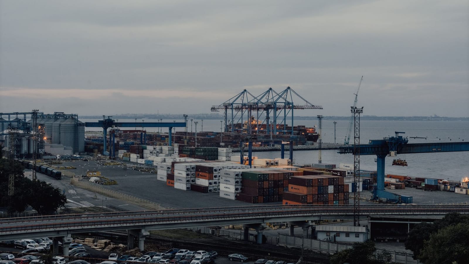 Aerial view of Odesa port, showcasing cranes, containers, and industrial activity at sunset.