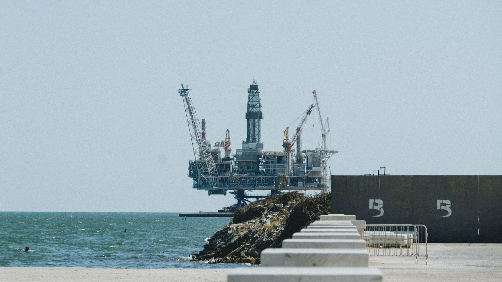 Distant view of an offshore oil rig with cranes on a sunny day.