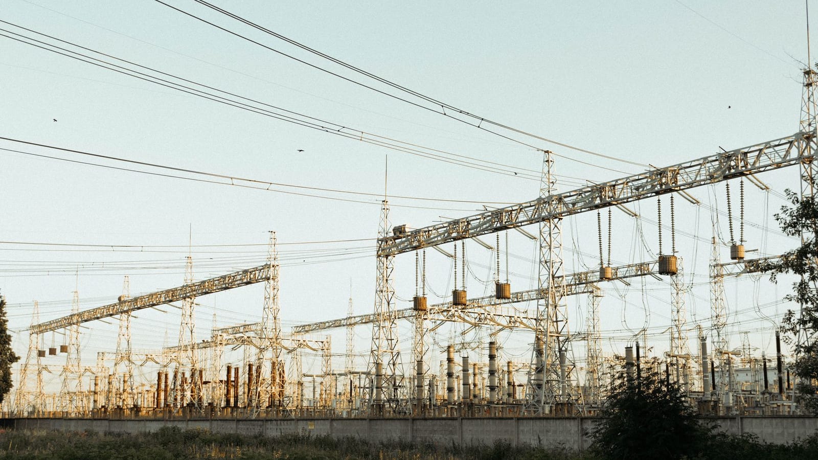 A wide view of an industrial electrical substation with power lines and towers outdoors.
