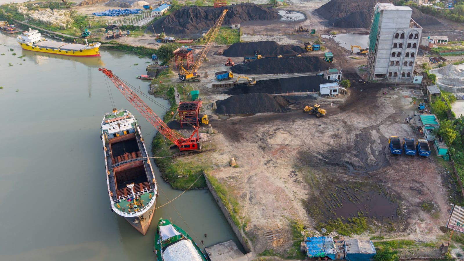 Aerial view of a bustling industrial port with ships and cranes in Dhaka, Bangladesh.