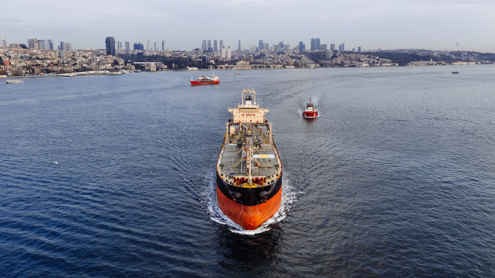 A stunning aerial shot of a cargo ship navigating the Bosphorus Strait in Istanbul, Turkey, with a city skyline.