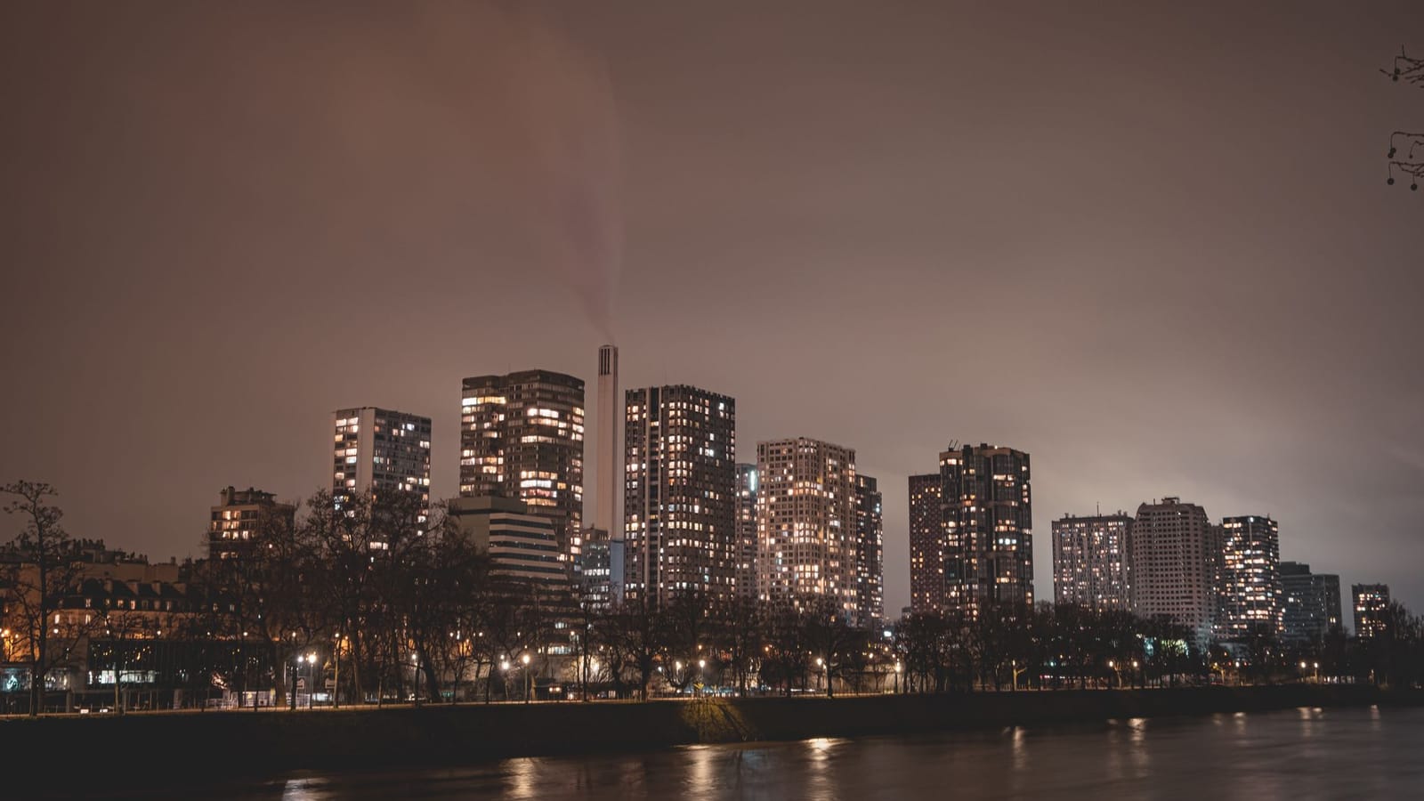 Captivating nighttime view of Paris skyline with illuminated skyscrapers along the river.